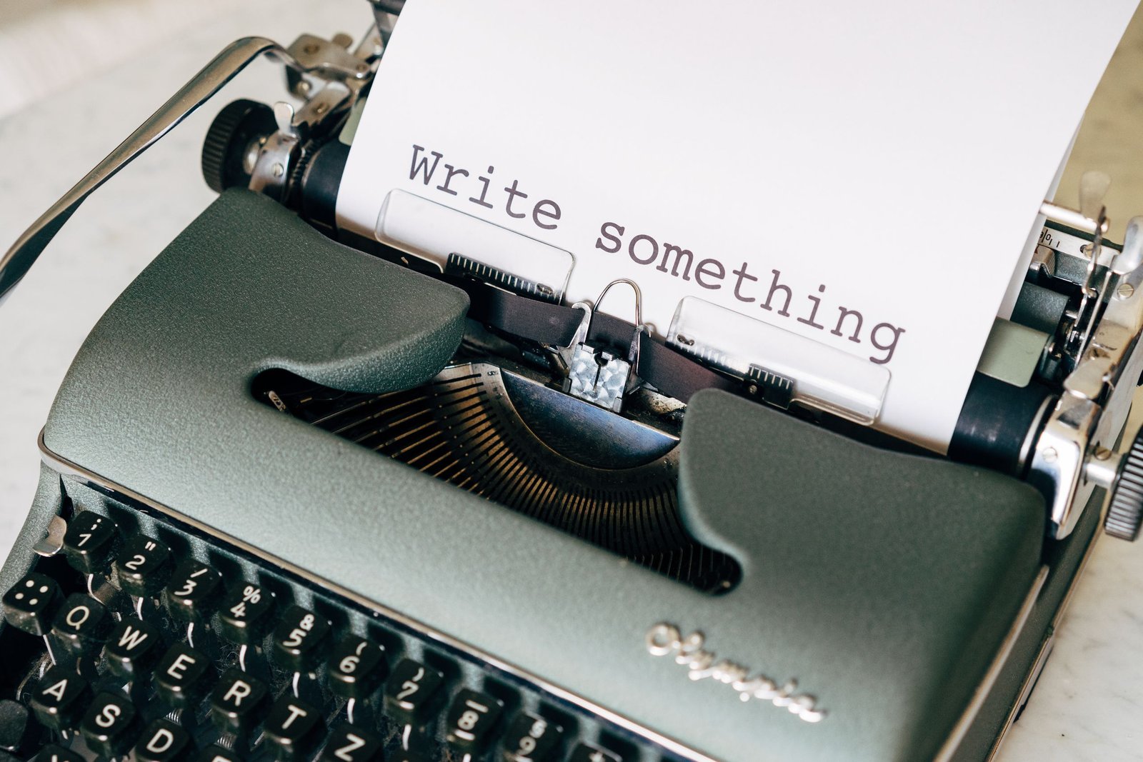 A close-up of a vintage typewriter with 'Write something' typed on paper.