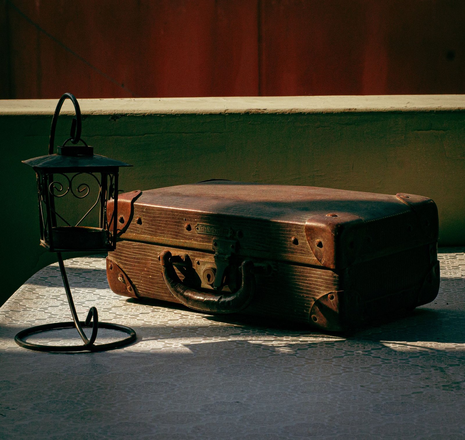 A vintage leather suitcase paired with a classic lamp on a textured table in Lima's Callao district.