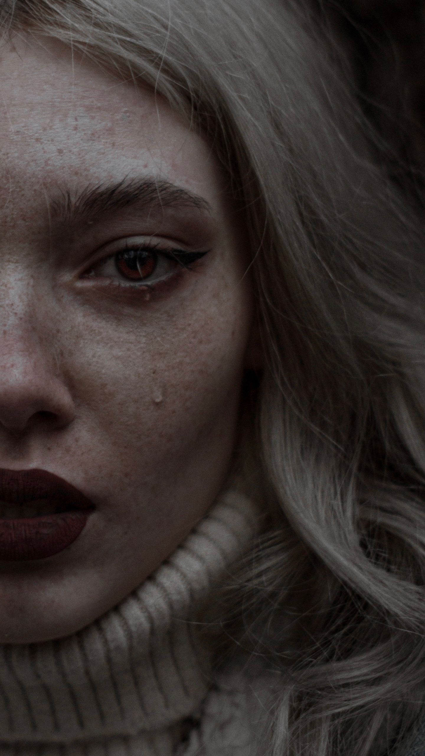 Close-up of a woman's face with tear, expressing deep emotion and sadness.