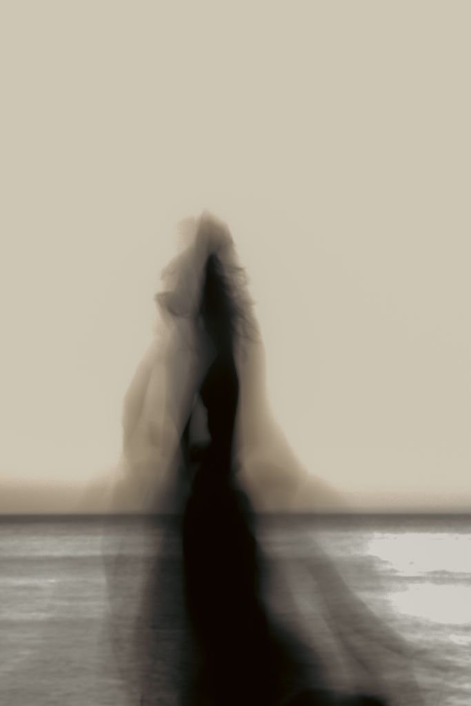 Ethereal silhouette of a woman amid misty seascape at sunset, capturing a haunting tranquility.